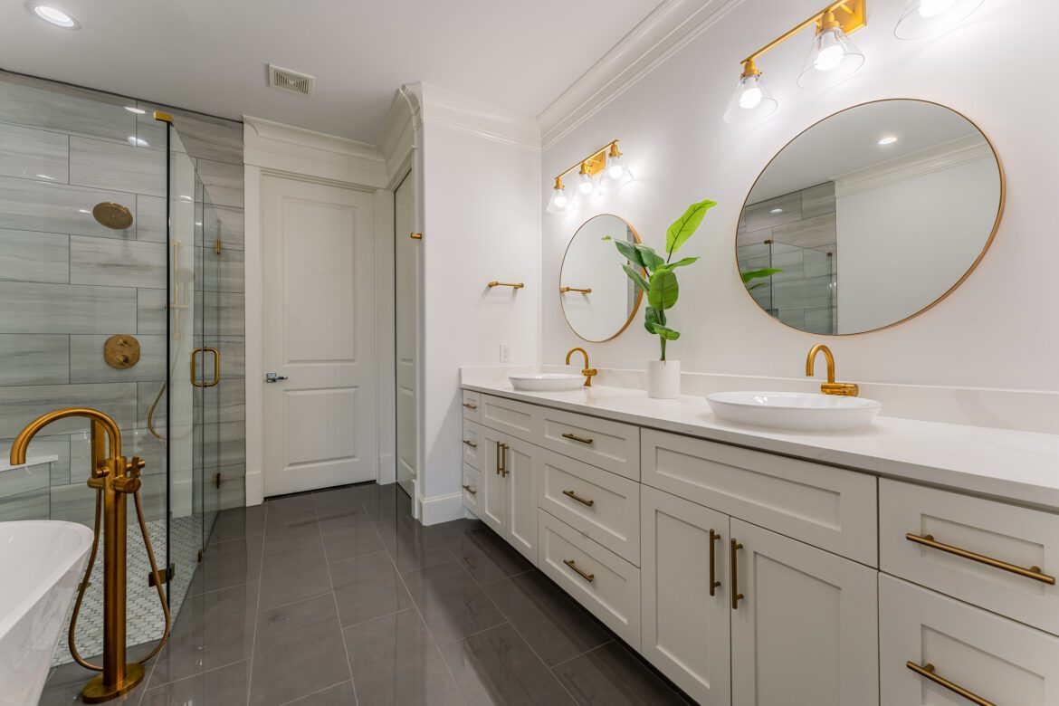 bathroom remodel completed by gambone's custom home improvements. double vanity with golden framed mirrors and golden fixtures, shoer and stand alone bathtub to the left.